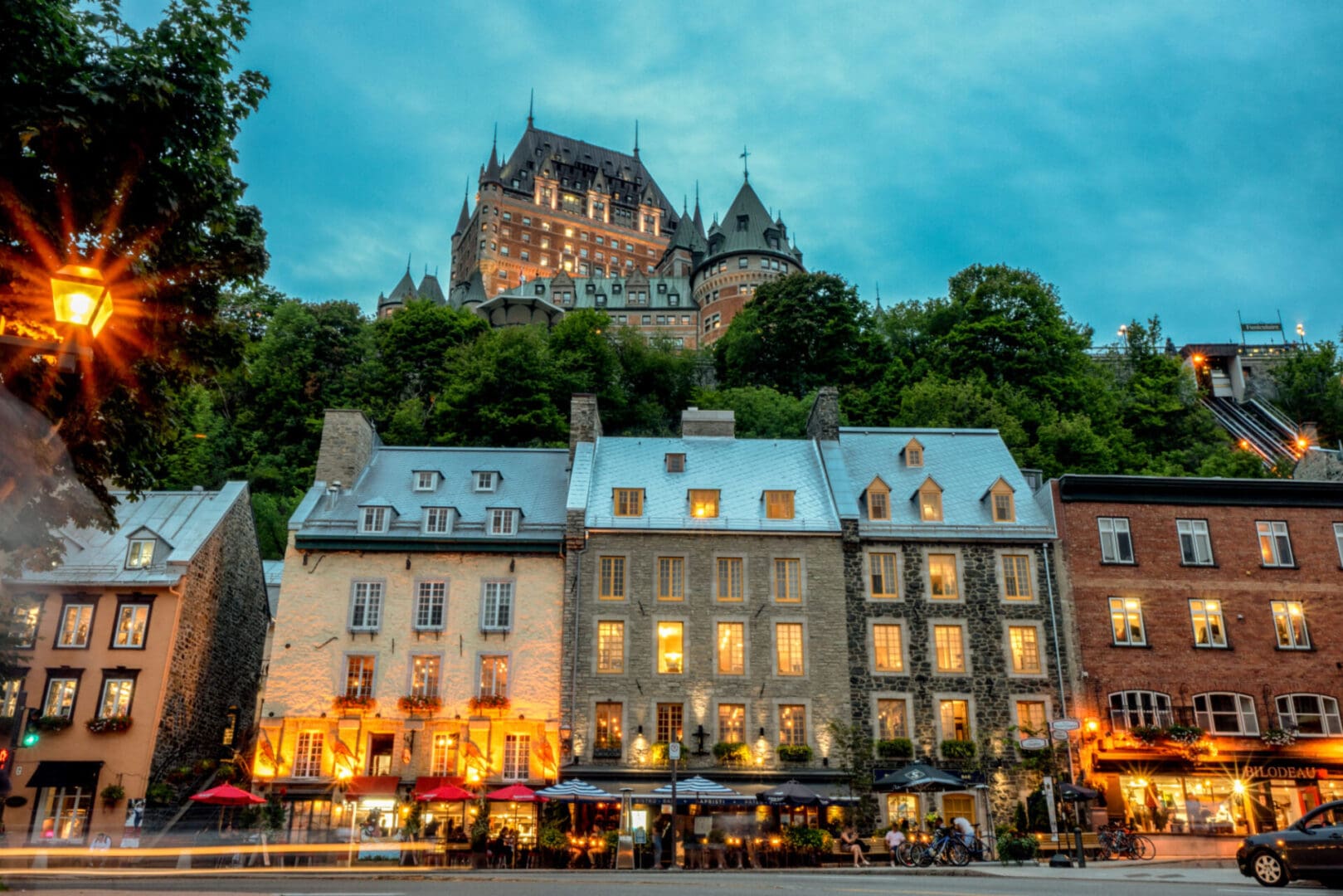 Historic buildings under illuminated castle at dusk.