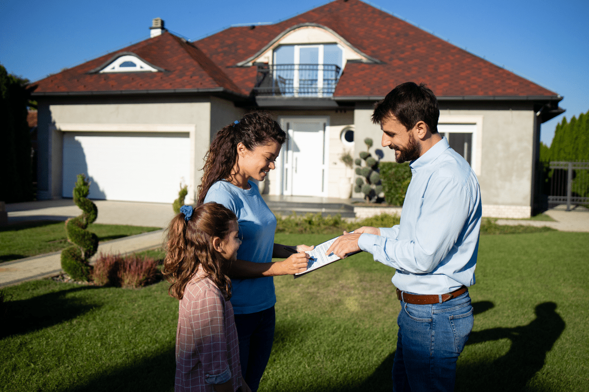 Family discussing paperwork outside suburban house.