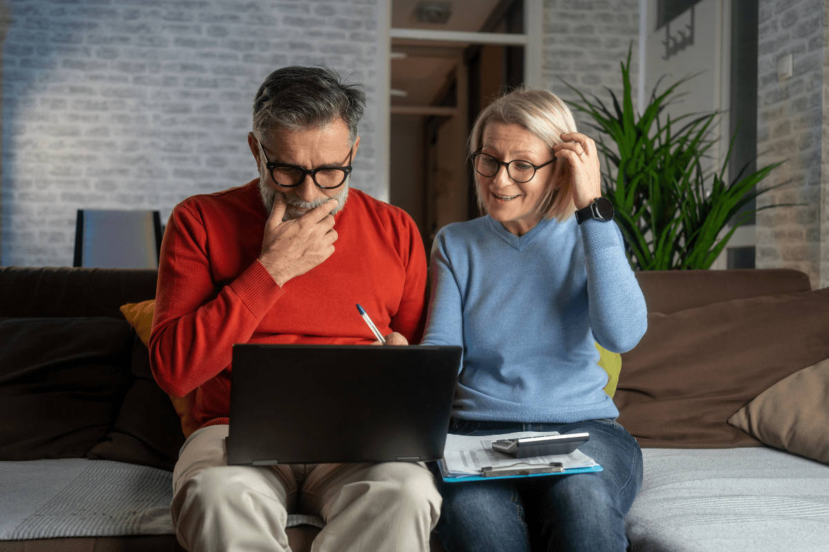 Older couple using a laptop together on couch.